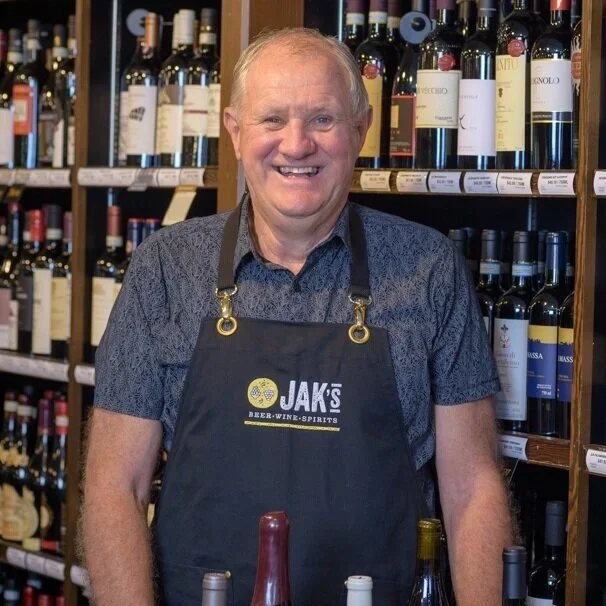 John Kettlewell, Chairman and founder of JAK's Beer Wine Spirits, standing in front of a wine shelf in a JAK's store in Vancouver