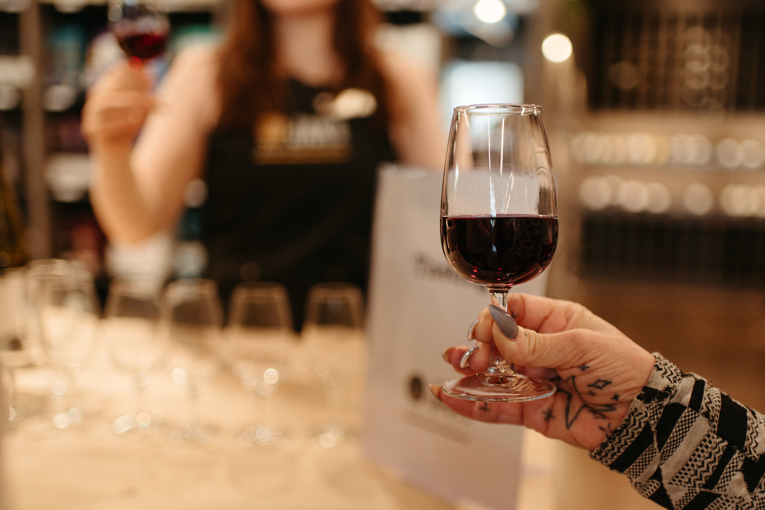 A hand holding a glass of red wine, representing JAK's Beer Wine Spirits company value of Learning and product knowledge