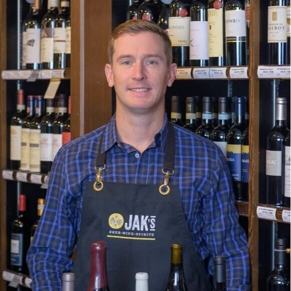 Geoff Dear, (John's Son-in-law) Shareholder at JAK's Beer Wine Spirits, standing in front of a wine shelf in a JAK's store in Vancouver