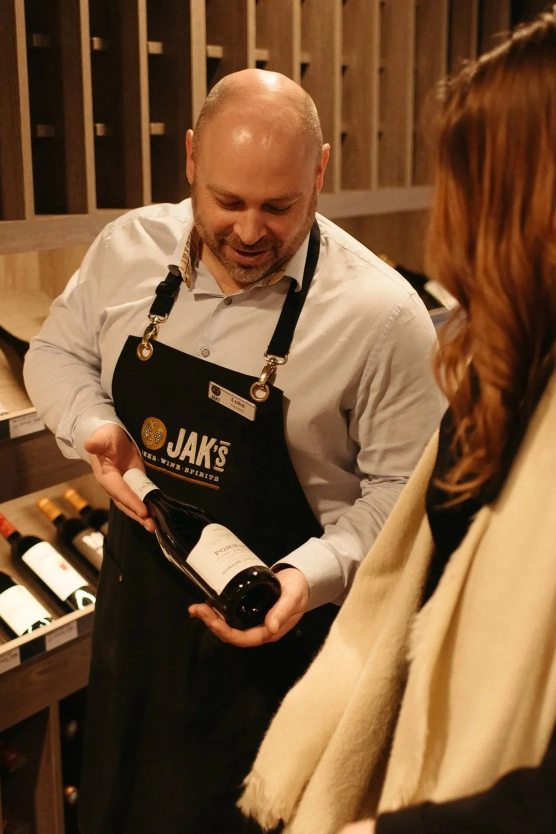 JAK's Beer Wine Spirits staff member recommending a bottle of red wine to a customer in store