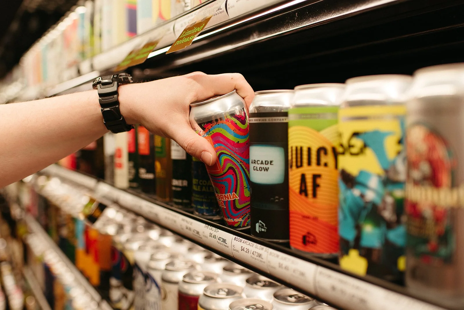 Hand selecting a craft canned beer from the fridge at a JAK's Beer Wine Spirits store in Vancouver