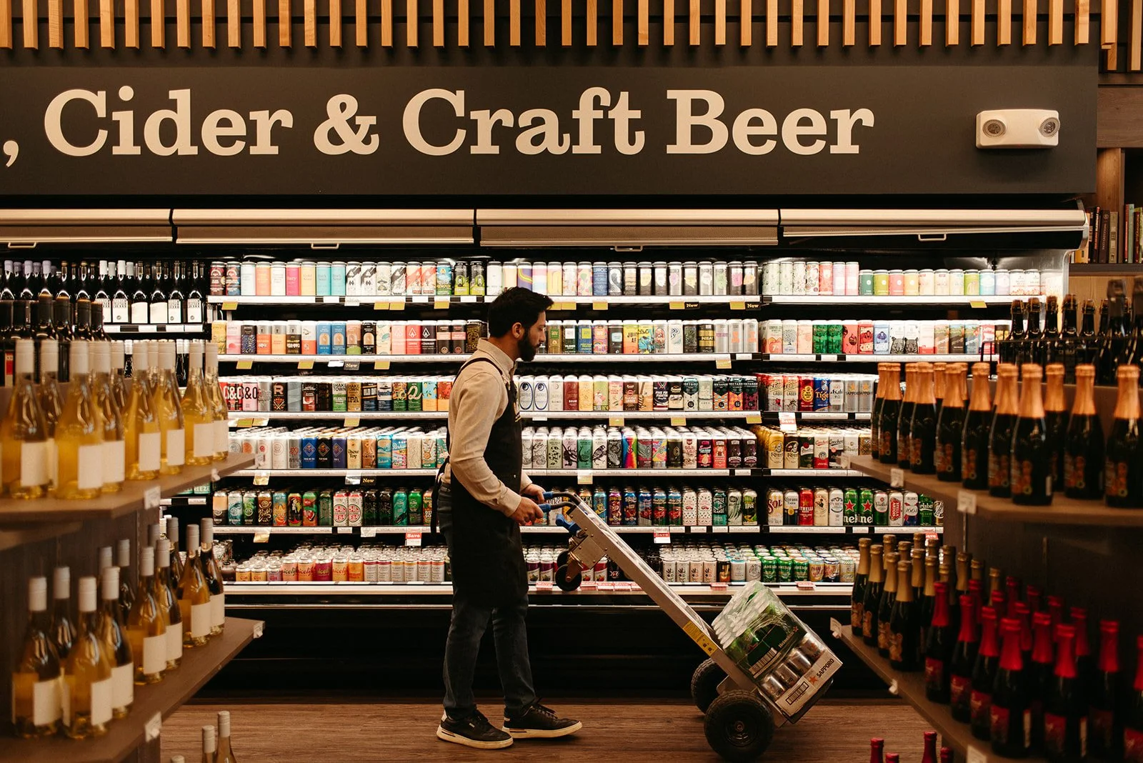 JAK's Beer Wine Spirits staff member stocking the craft beer aisle in a Vancouver liquor store