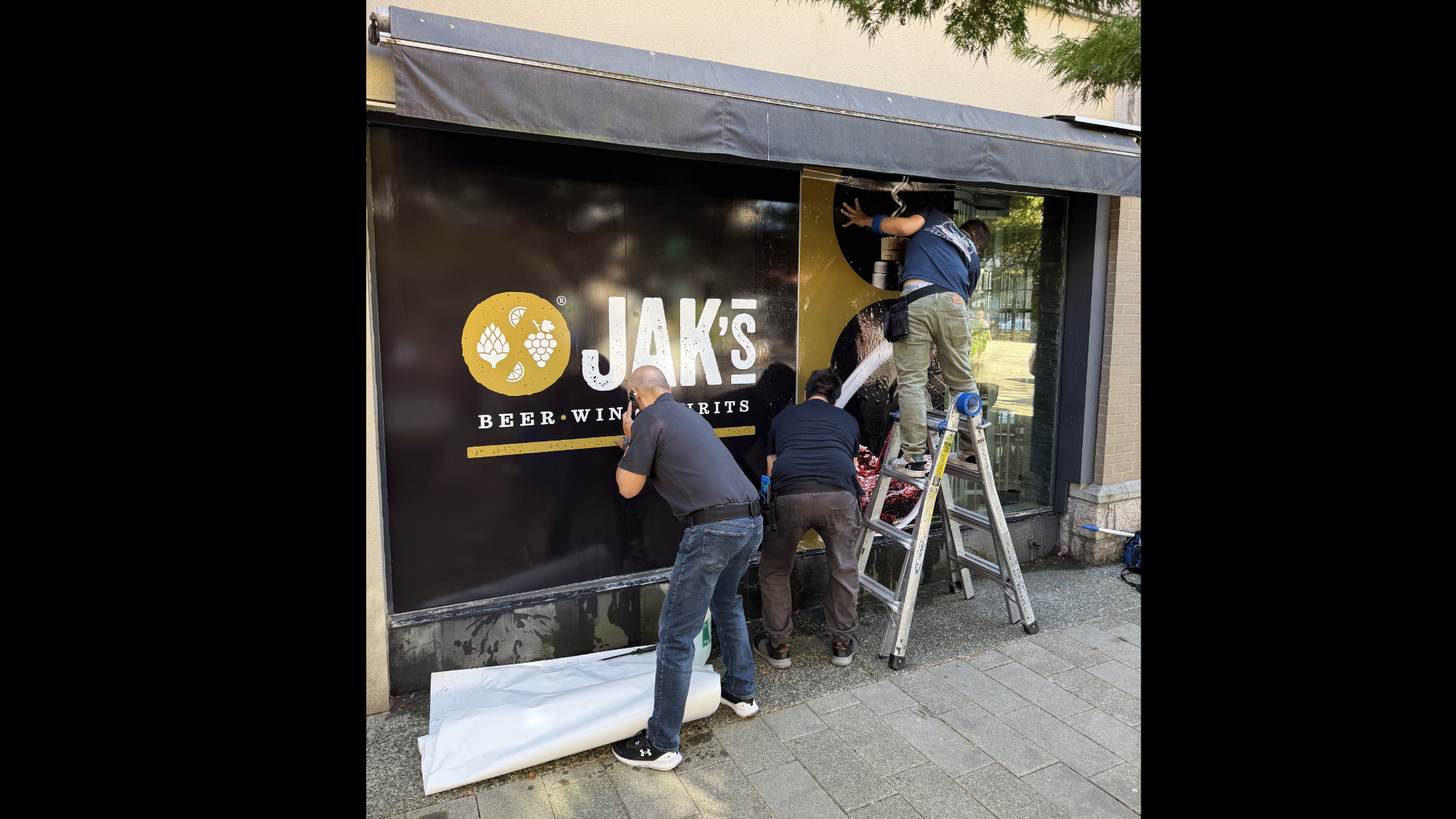 JAK's Beer Wine Spirits Kitsilano store opening, with staff installing signage on the new Vancouver location