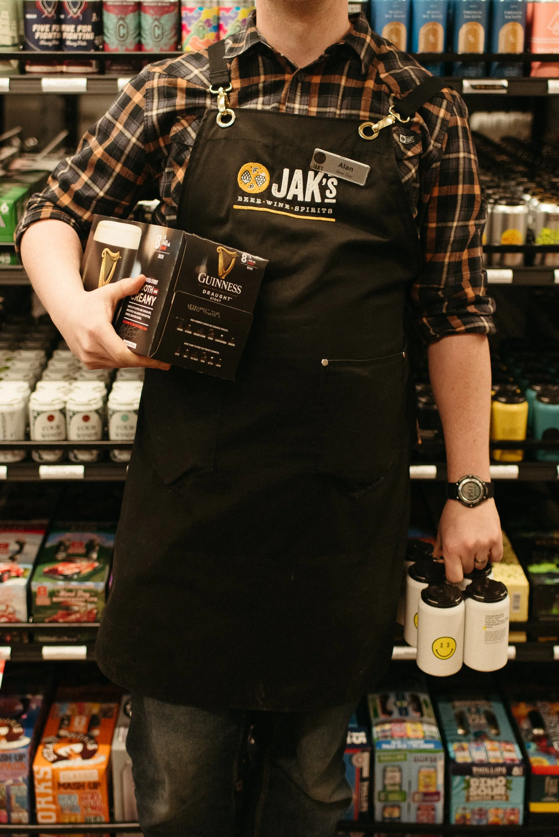 JAK's Beer Wine Spirits staff member holding a Guinness multipack in a Vancouver liquor store