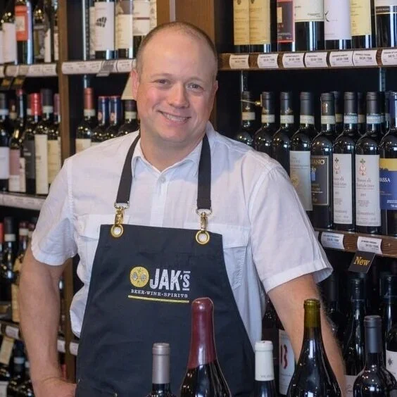Matt Kettlewell, (John's Son) Shareholder at JAK's Beer Wine Spirits, standing in front of a wine shelf in a JAK's store in Vancouver 