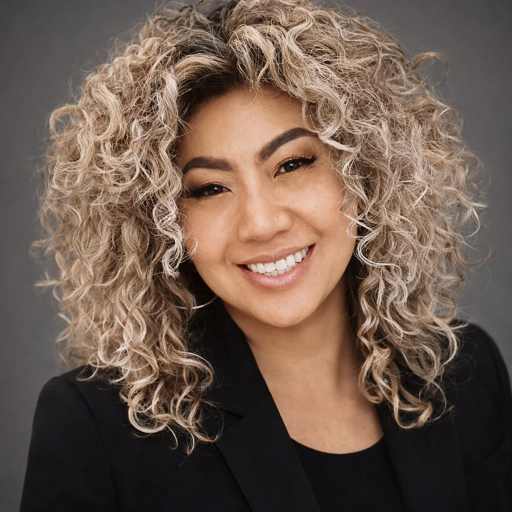 A woman with curly blonde hair smiling at the camera