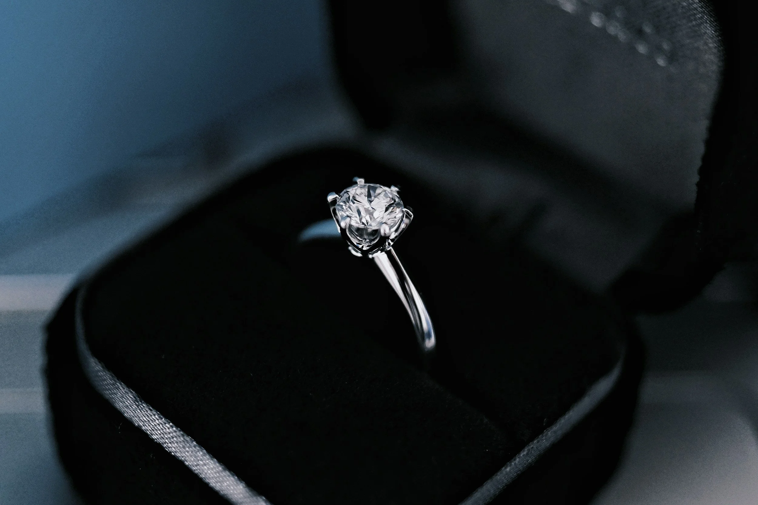 A close-up of a diamond engagement ring with a solitaire diamond in a black ring box.