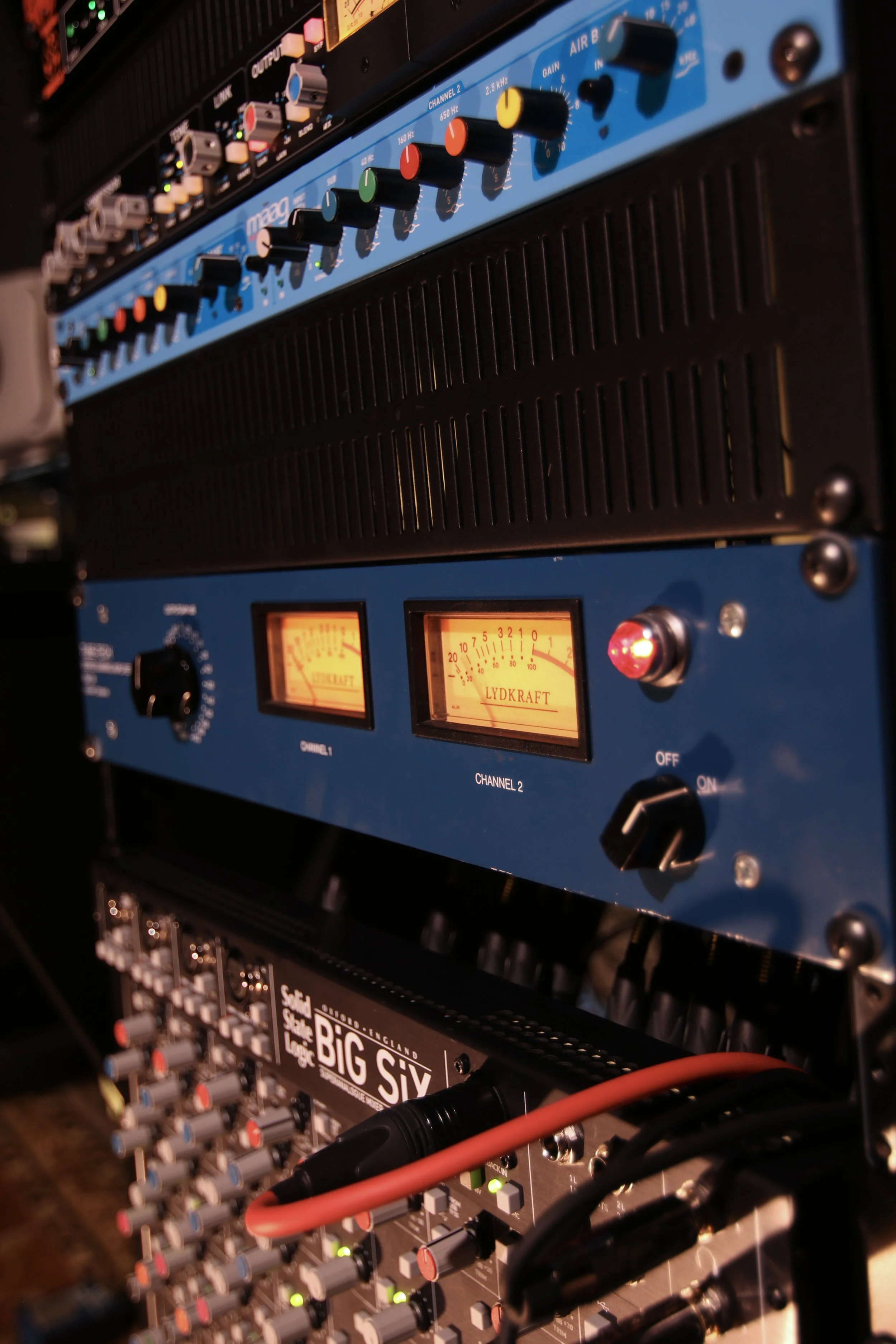 Close-up of audio sound equipment with various knobs, meters, and cables connected.