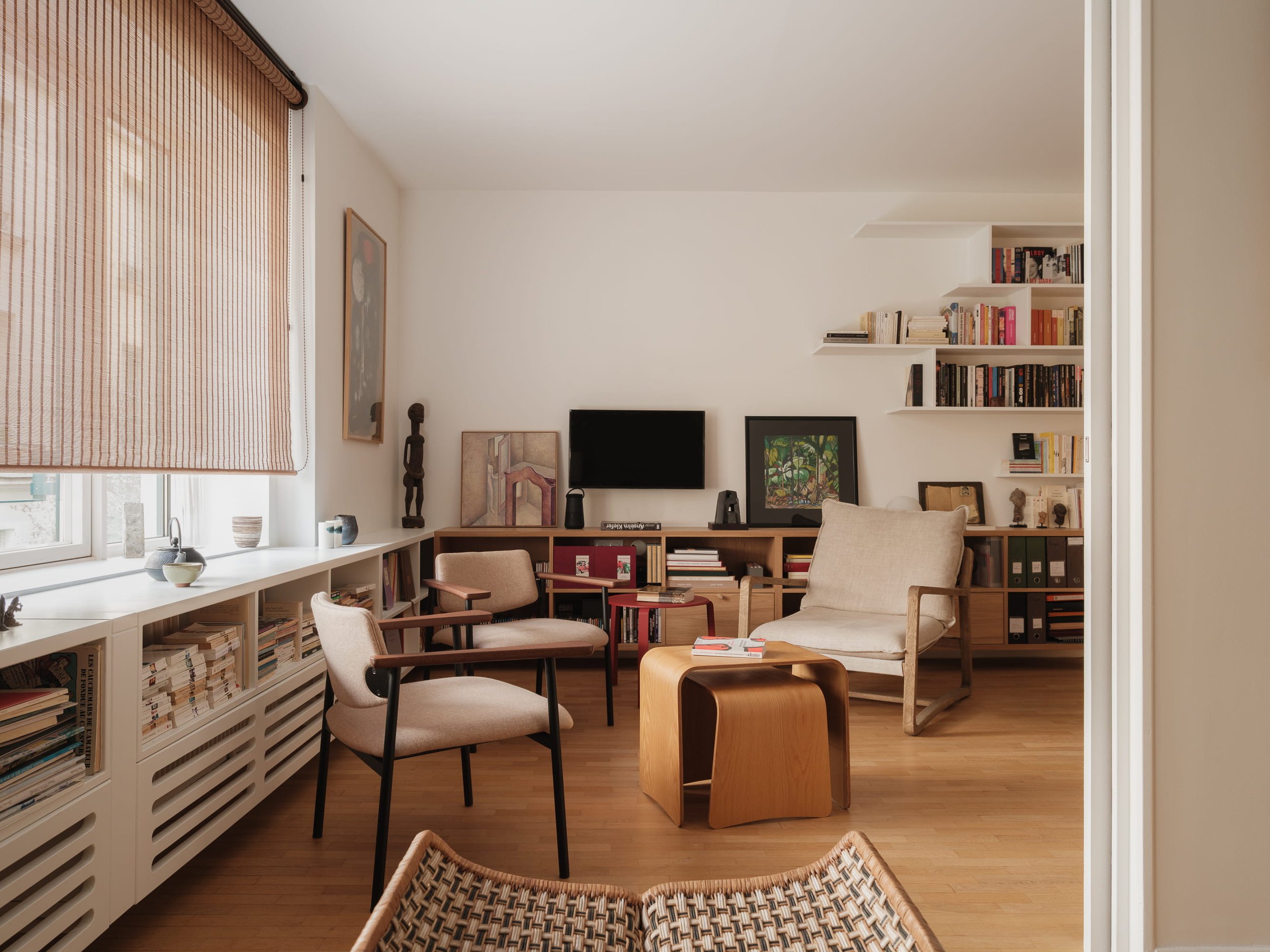 Rénovation complète. Architecture d'intérieur à Paris. Bibliothèque sur mesure en bois blanc et bois chêne, fauteuil Flamand Paris. Décoration d'intérieur