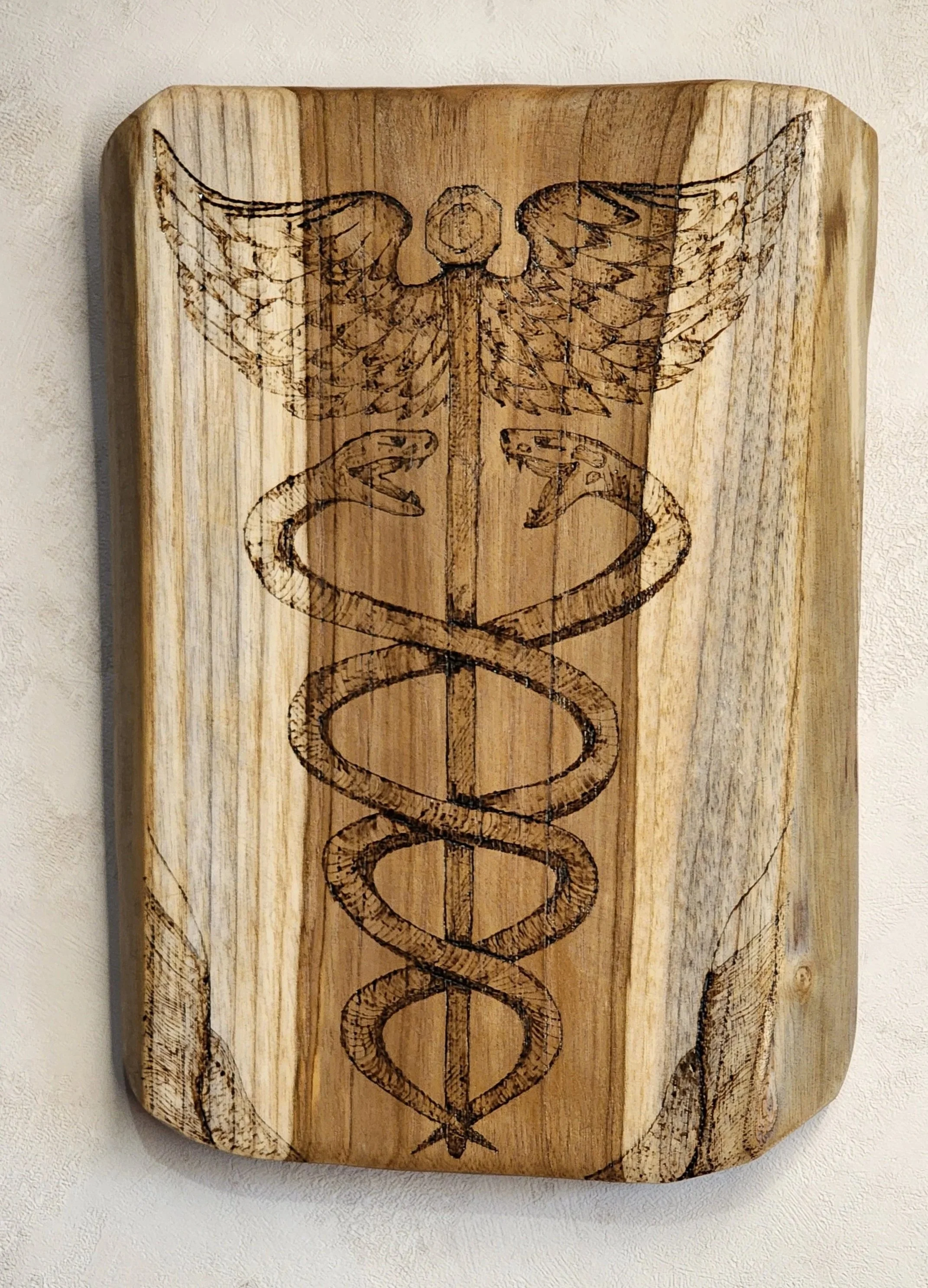 Bois pyrogravé représentant le symbole du caducée d'Hermès. Elaura Donnadieu, graphiste, illustratrice et artiste peintre.