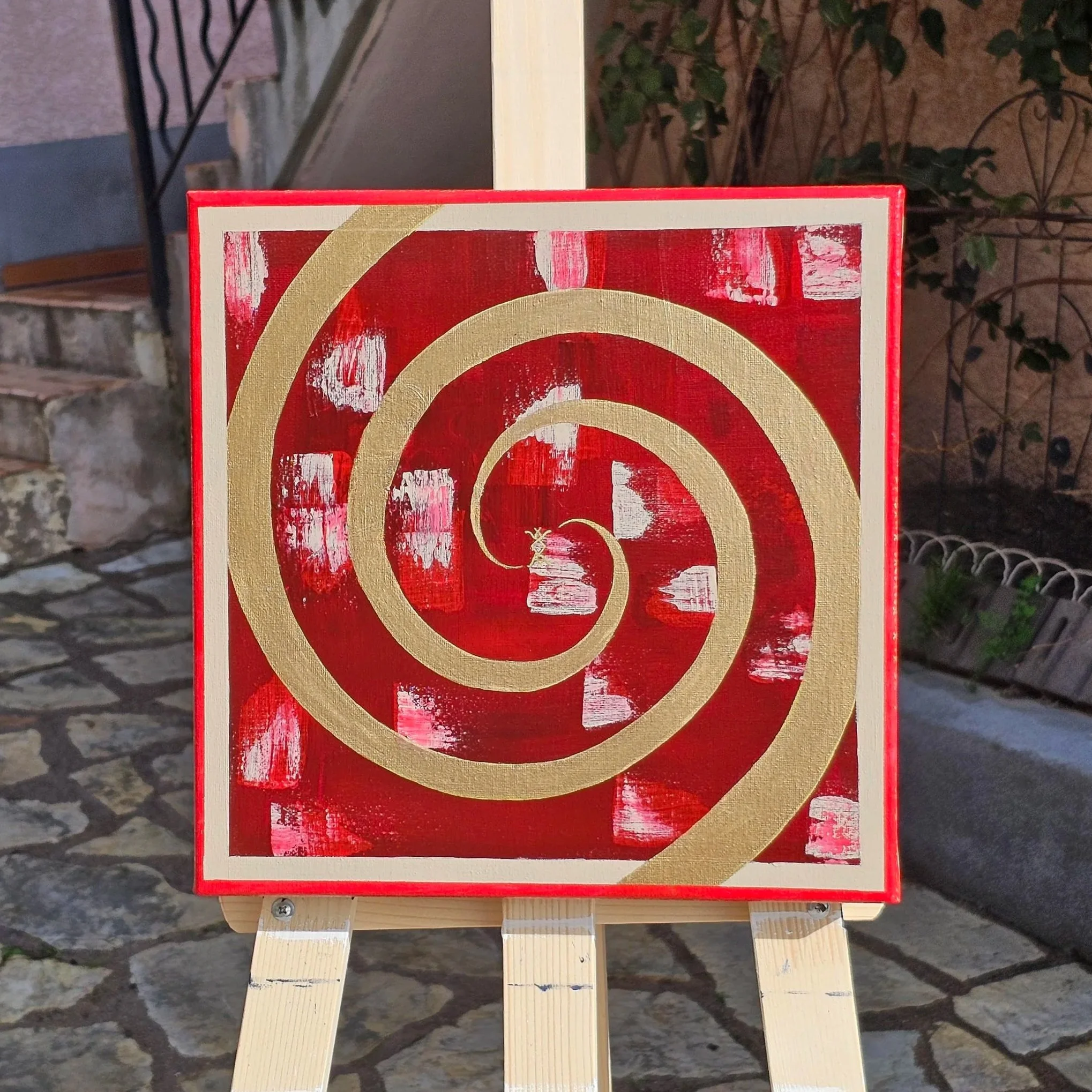 Tableau artistique avec un fond rouge, des spirales en or et des rectangles blancs peints de manière abstraite avec une runes russe de l'Amour. "Le temps d'aimer". Elaura Donnadieu, graphiste, illustratrice et artiste peintre.