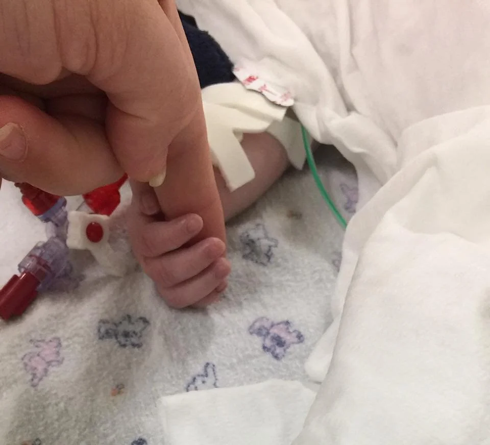 Shyna holding her mum's hand in a hospital bed