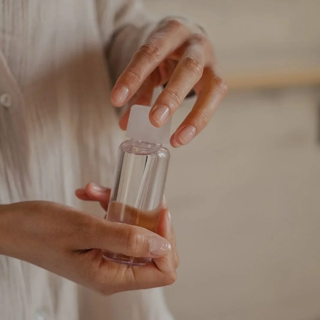 Nahaufnahme von Händen, die einen kleinen Behälter mit Massage-Öl halten.