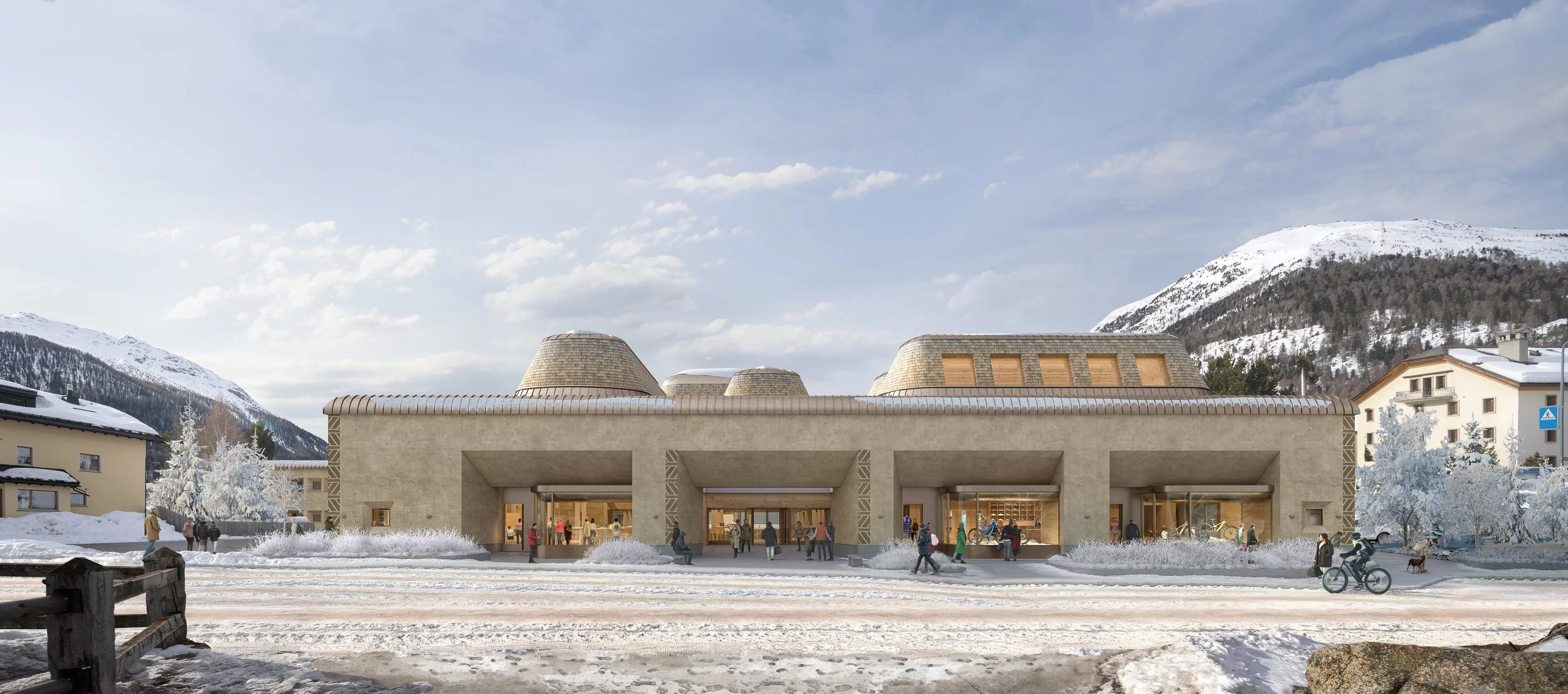 A modern building in a snowy mountain town with people walking and riding bikes in front of it.