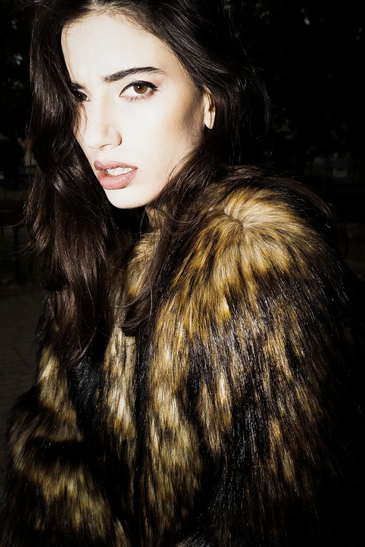 Close-up of a woman with dark brown hair and hazel eyes wearing a fur coat.