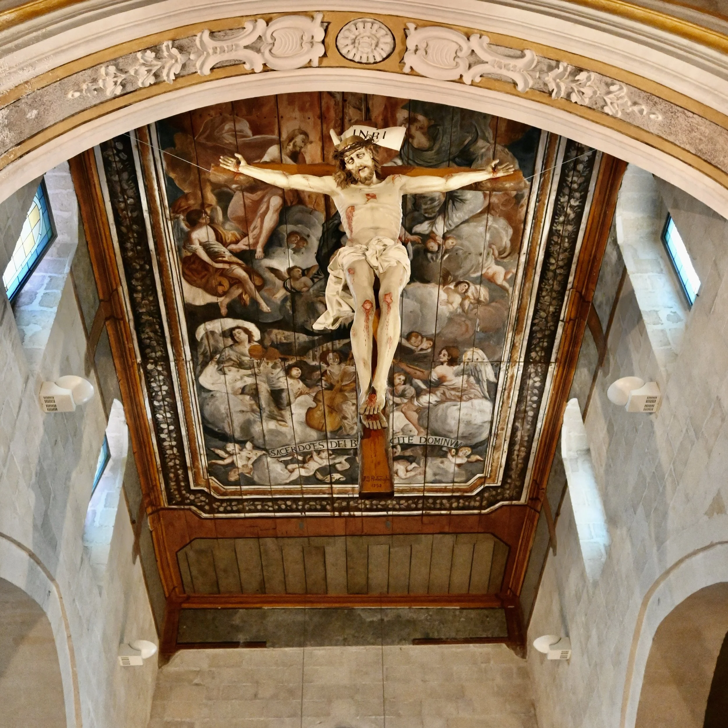 Seville Cathedral:  Jesus on cross enveloped by elaborate ancient art wall behind. Italy 