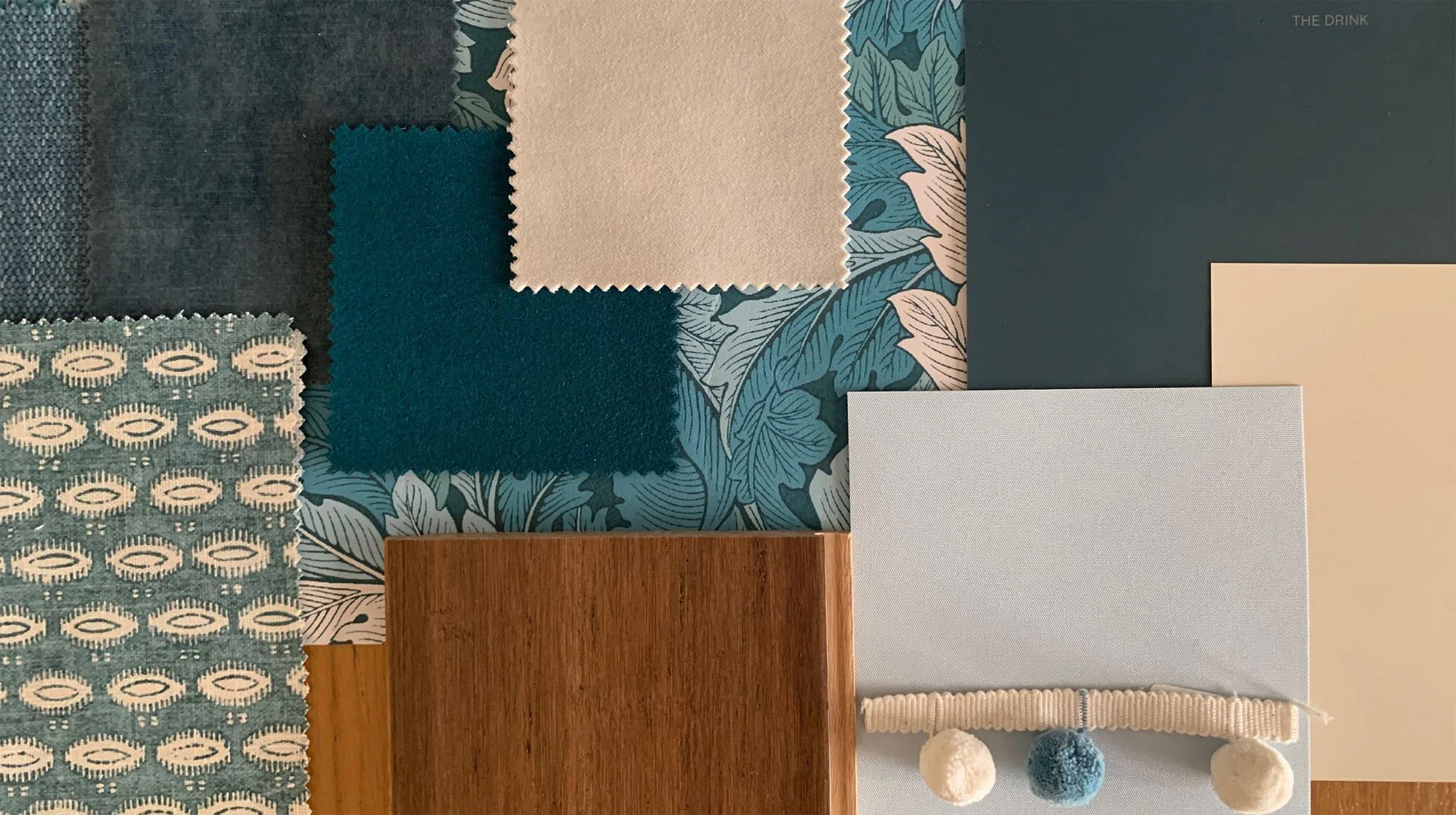 Interior design mood board with blue and white fabric swatches, floral patterns, wood texture, and pom-pom trim.