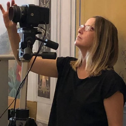 Donna che utilizza una macchina fotografica su tripiede in interni