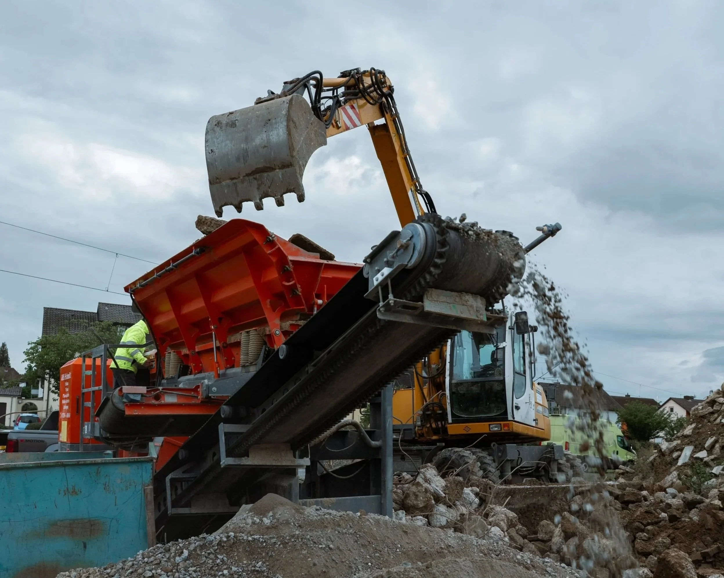 Baumaschinen und Bauarbeiter bei einer Baustelle, Erde wird bewegt, Wolken am Himmel.