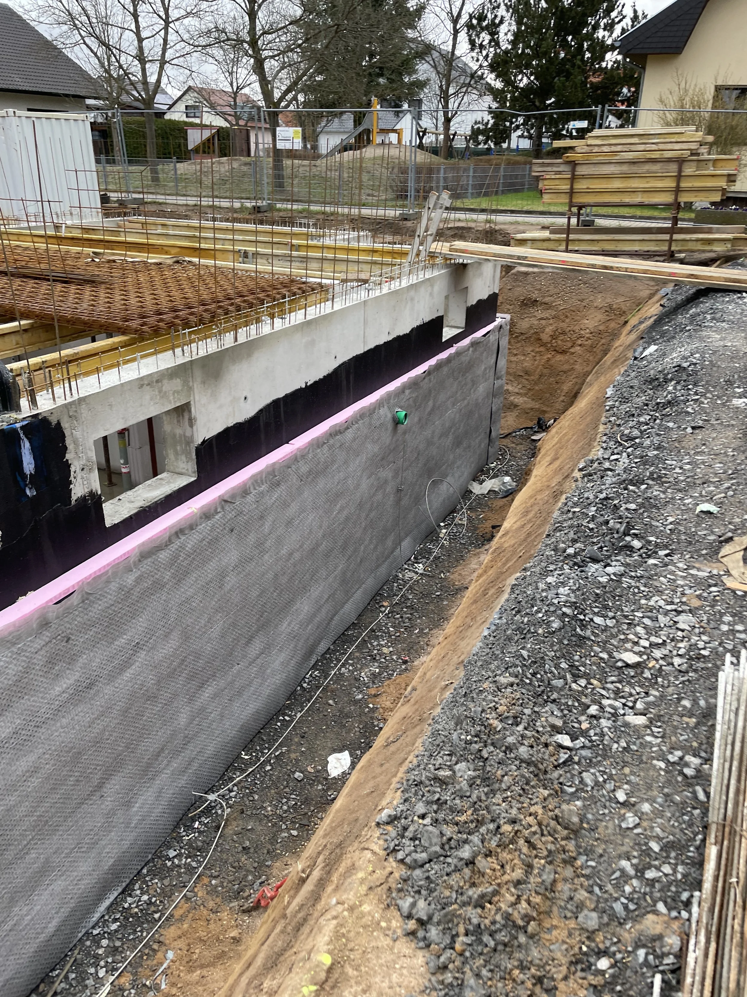 Baustelle mit Fundamentarbeiten, isolierten Wänden und Baumaterialien