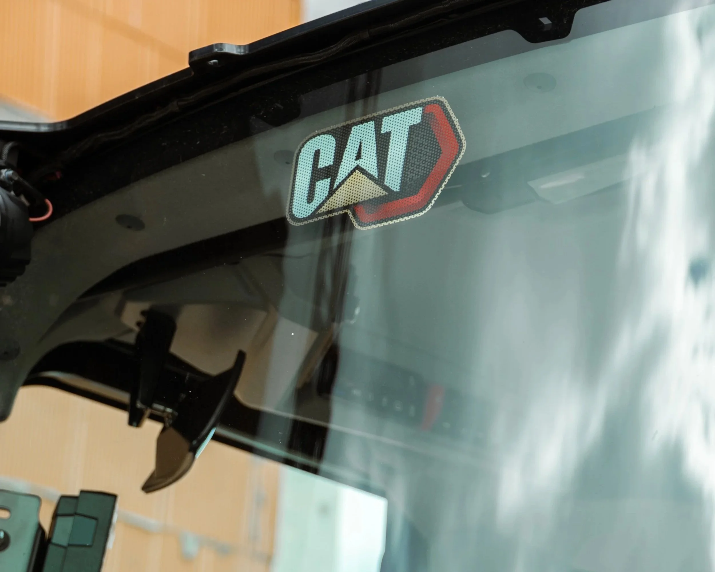 Ein Autofenster mit einem Sticker der Marke CAT (Caterpillar) auf dem Glas.