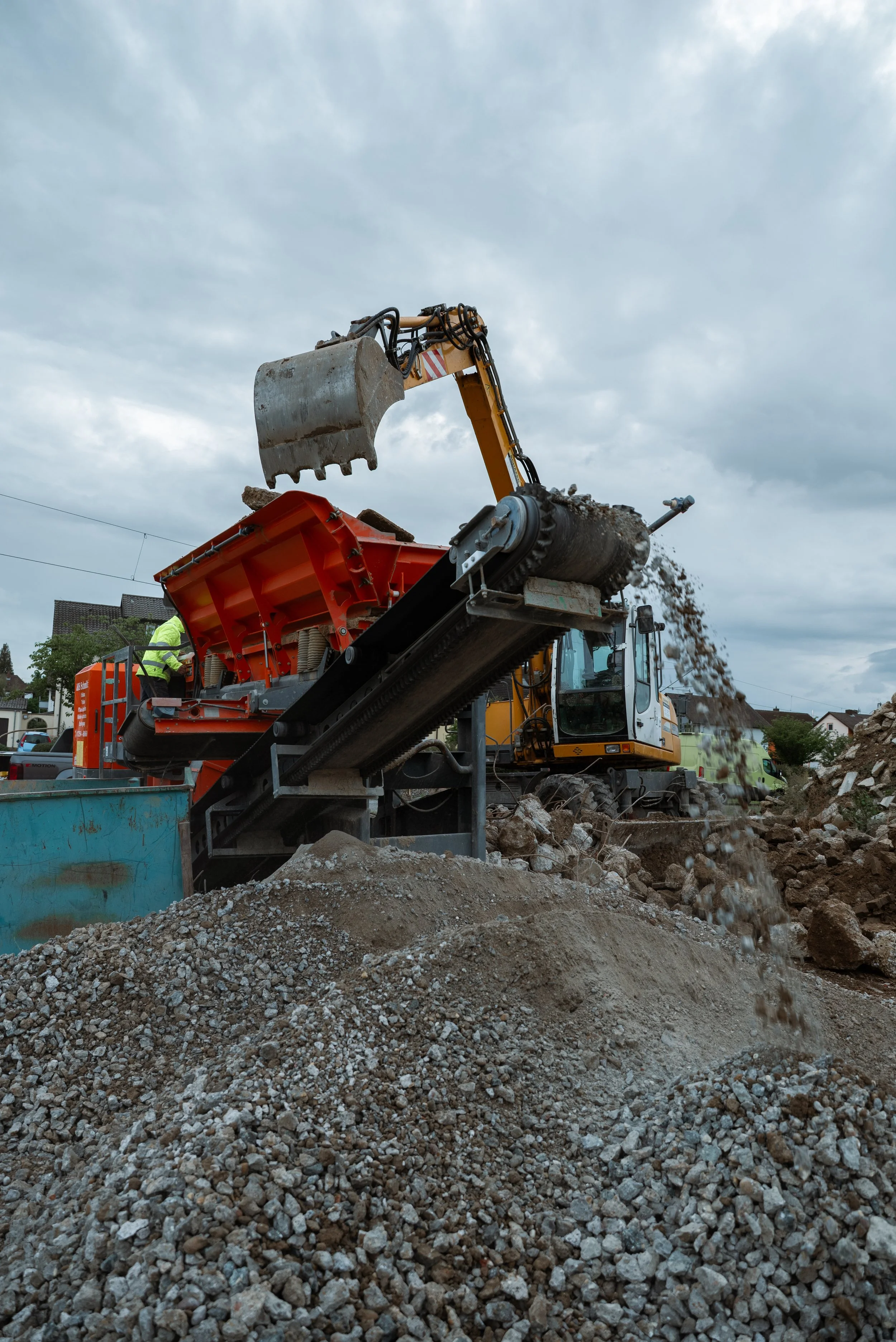 Baumaschine bei der Erdarbeiten, die Erde bewegt, mit Wolkenhimmel im Hintergrund.