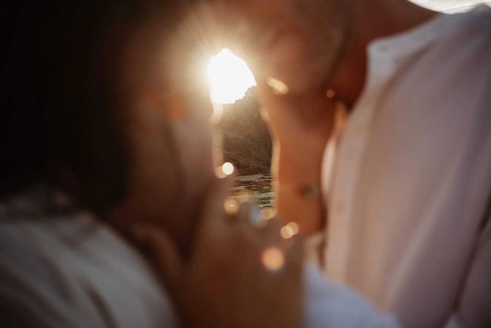 Close-up of a couple with the sun setting in the background, capturing their faces close to each other.