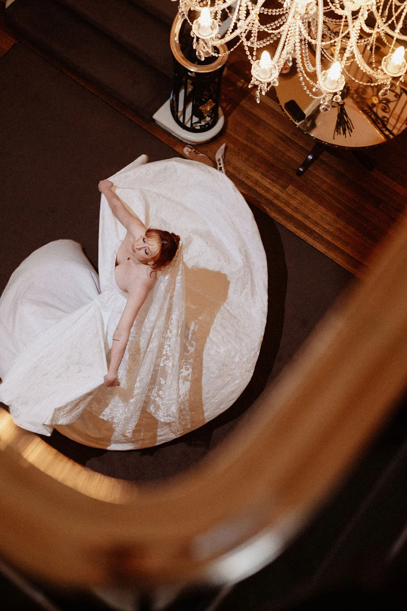 Photo of a bride dancing, twirling her dress down the stairs of a manor, from upstairs