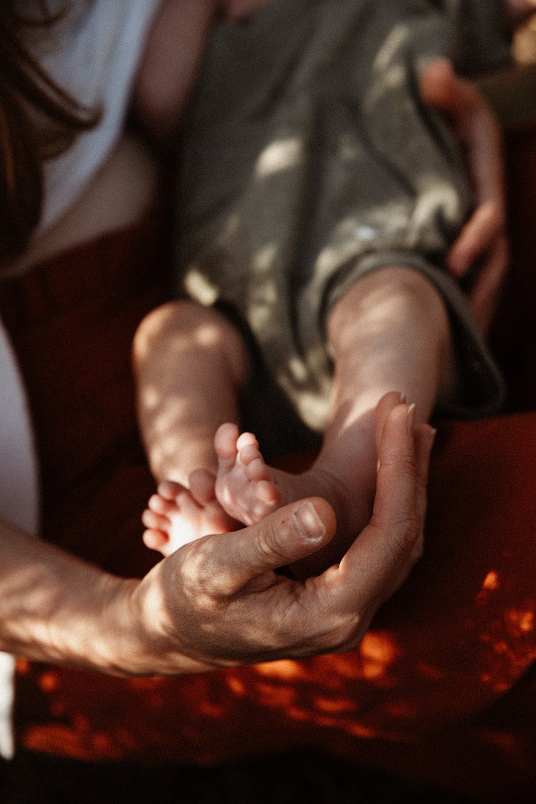 A person's hand gently holding a baby's tiny foot.
