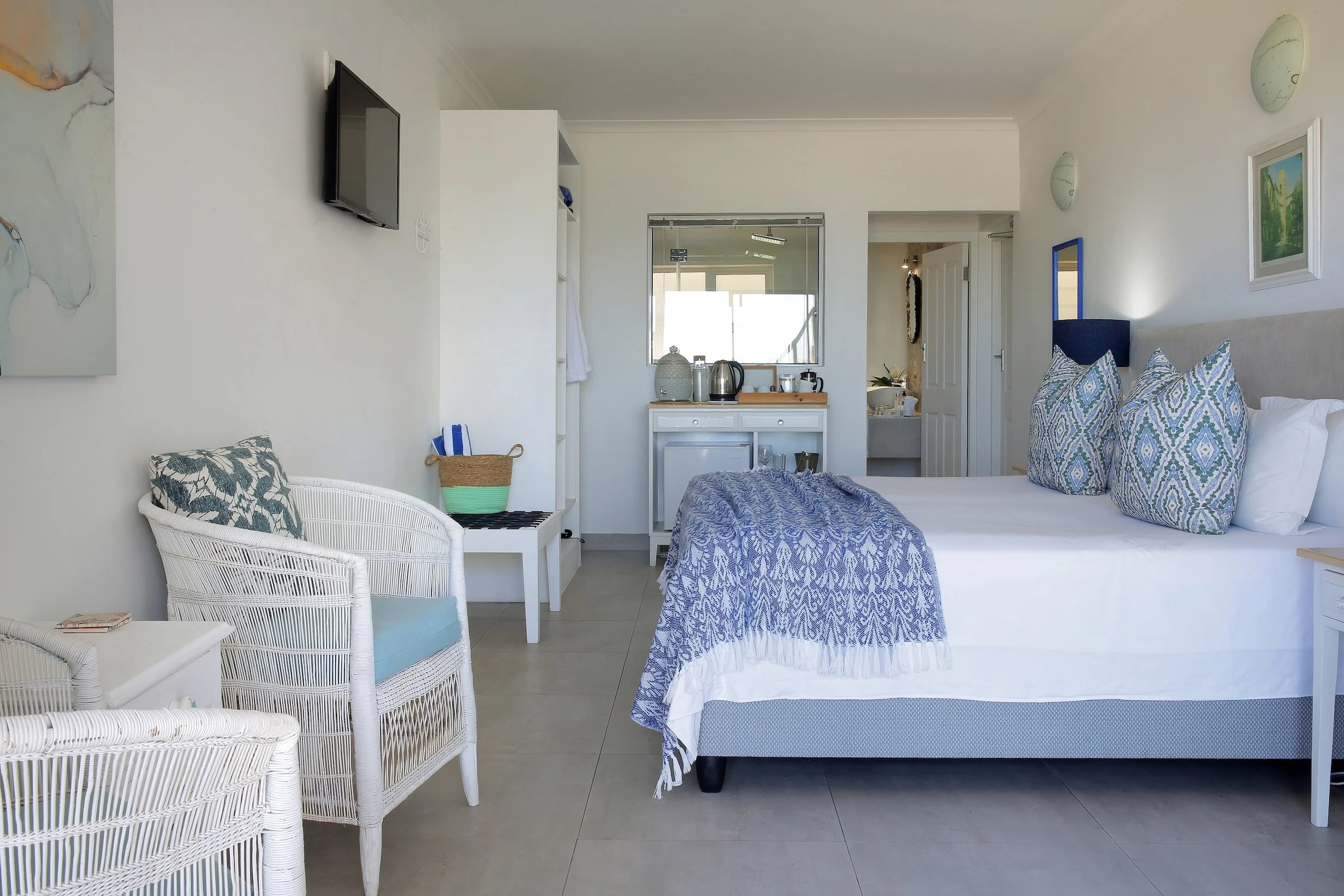 Light-filled upper-deck sea-facing room with king bed, lounge chairs and en-suite bathroom at Mykonos Luxury Guest House, St Francis Bay.