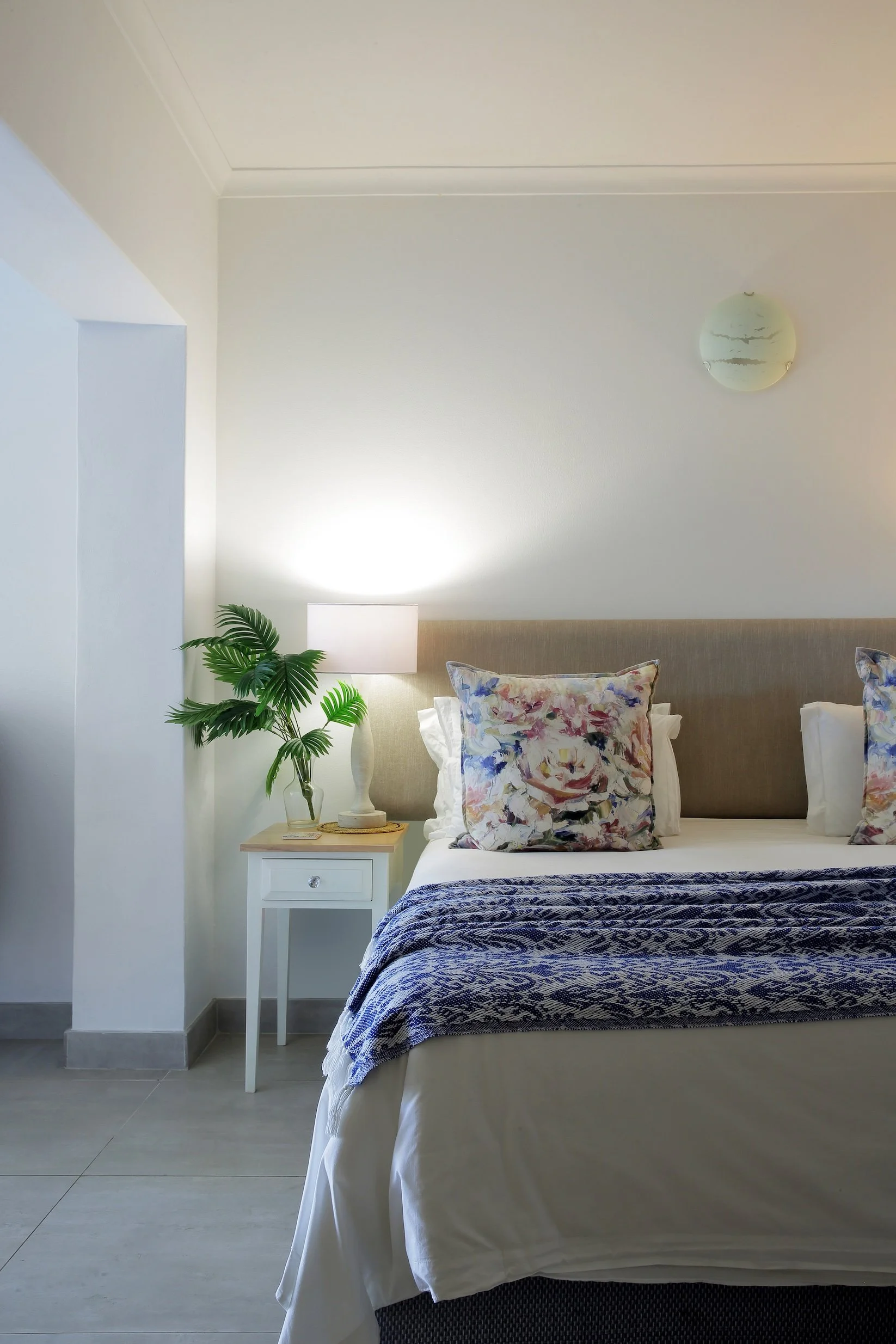 Bright coastal bedroom with king bed, floral cushions and bedside table at Mykonos Luxury Guest House, St Francis Bay.