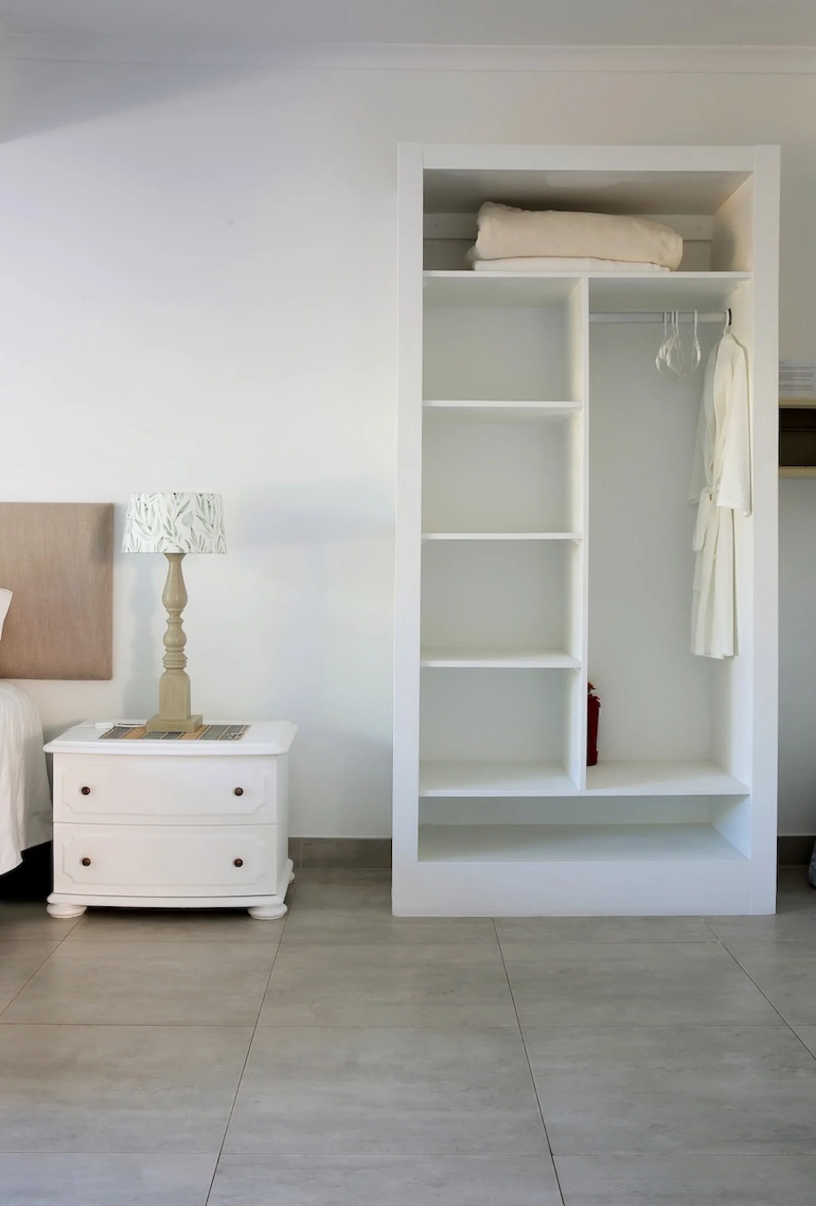 Open wardrobe and bedside table in deluxe sea-facing room at Mykonos Luxury Guest House, St Francis Bay.