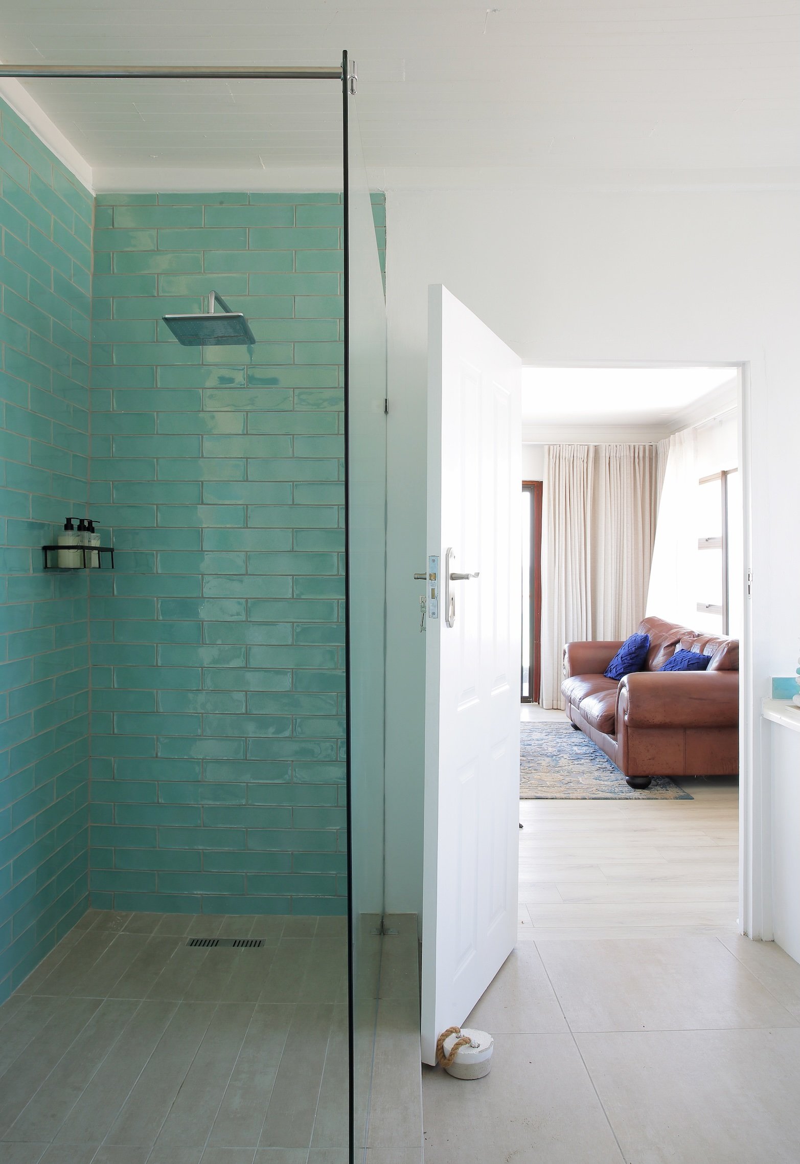 Walk-in rainfall shower with turquoise tiles in luxury St Francis Bay guest house suite.