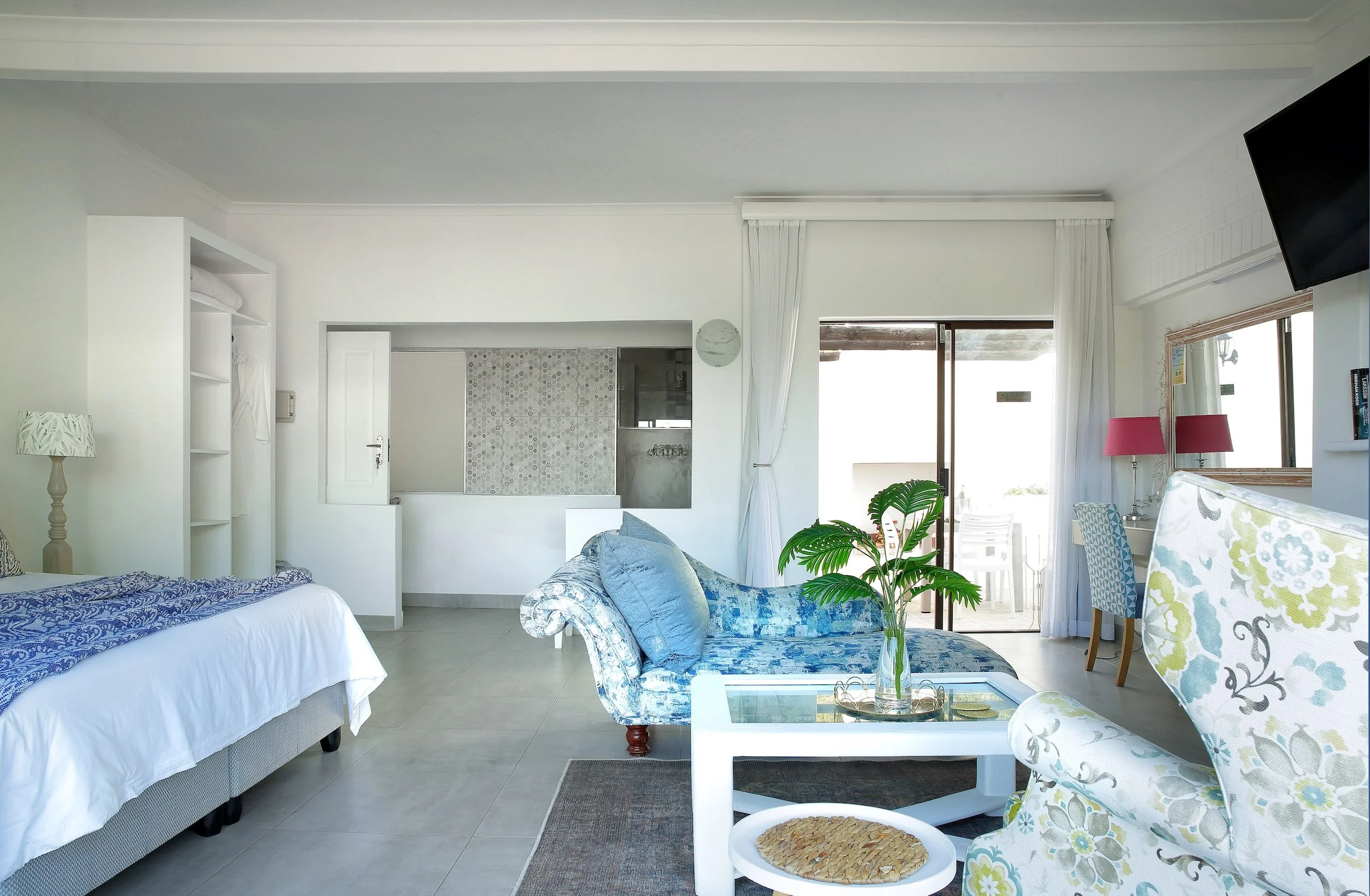 Deluxe sea-facing room with king bed, lounge seating and private patio at Mykonos Luxury Guest House in St Francis Bay.