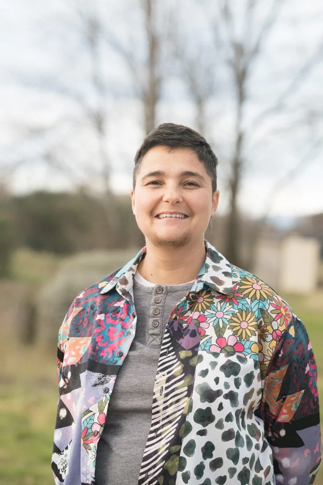 Jeune homme souriant portant une chemise à motifs floraux et animalier, en plein air.