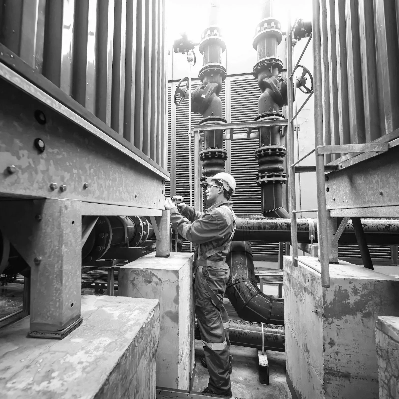 Industrial worker at a construction plant with pipe infrastructure, illustrating executive coaching for infrastructure leaders