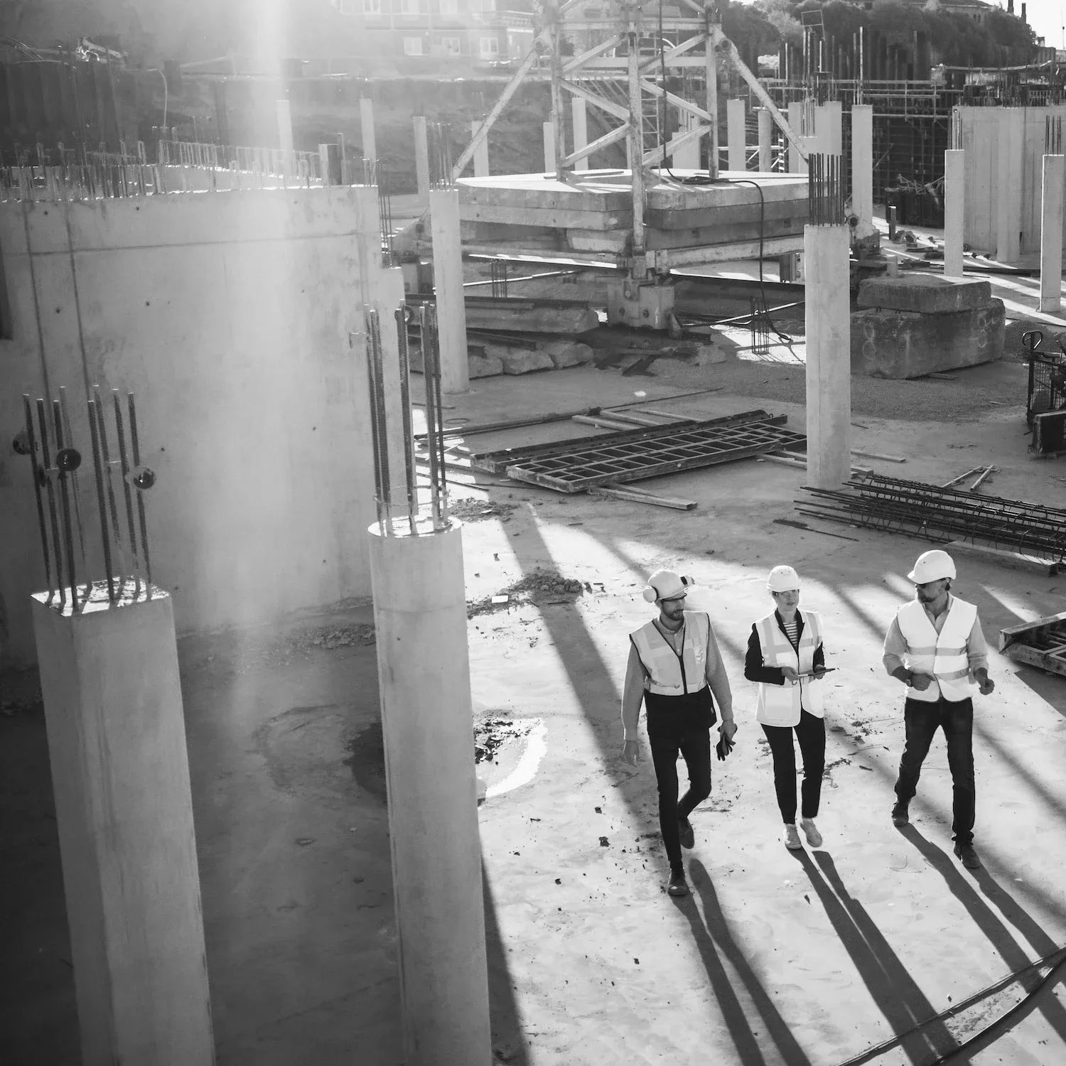 Three construction workers in high visibility vests walking on large construction site represent executive coaching in Bristol