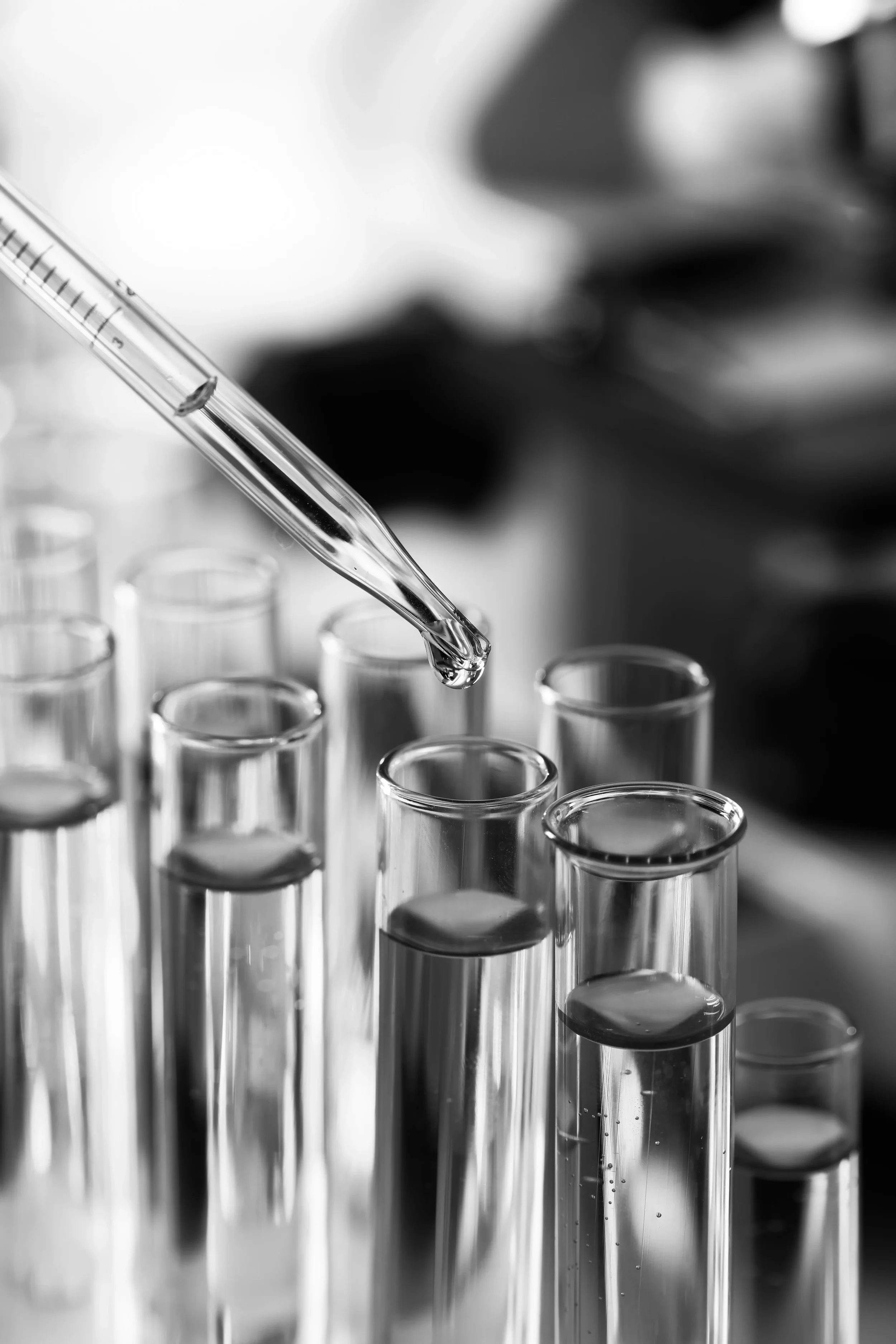 Pipette above pharmaceutical laboratory test tubes, representing executive coaching for life sciences leaders