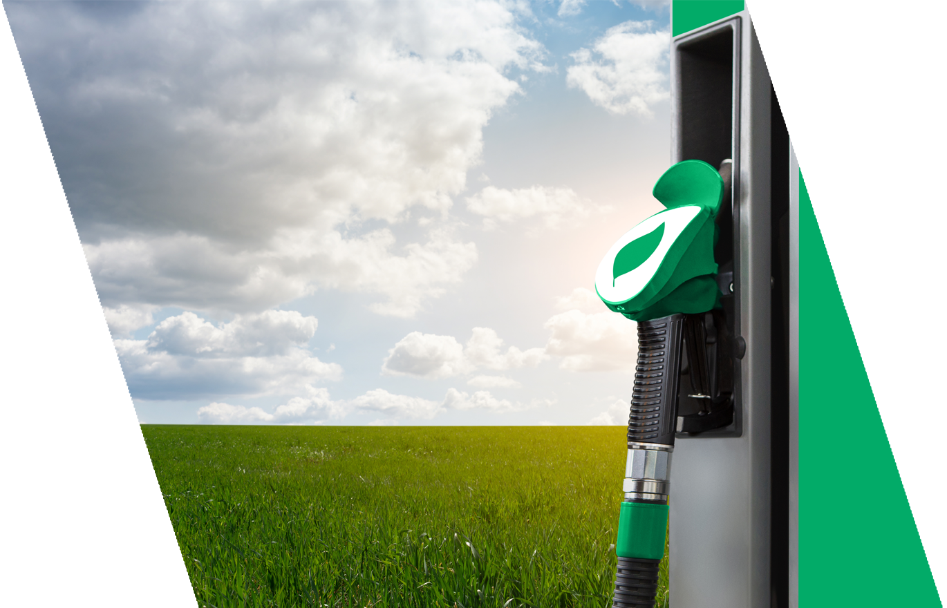 Gas pump with a green and white nozzle outdoors on a grassy field with a partly cloudy sky.