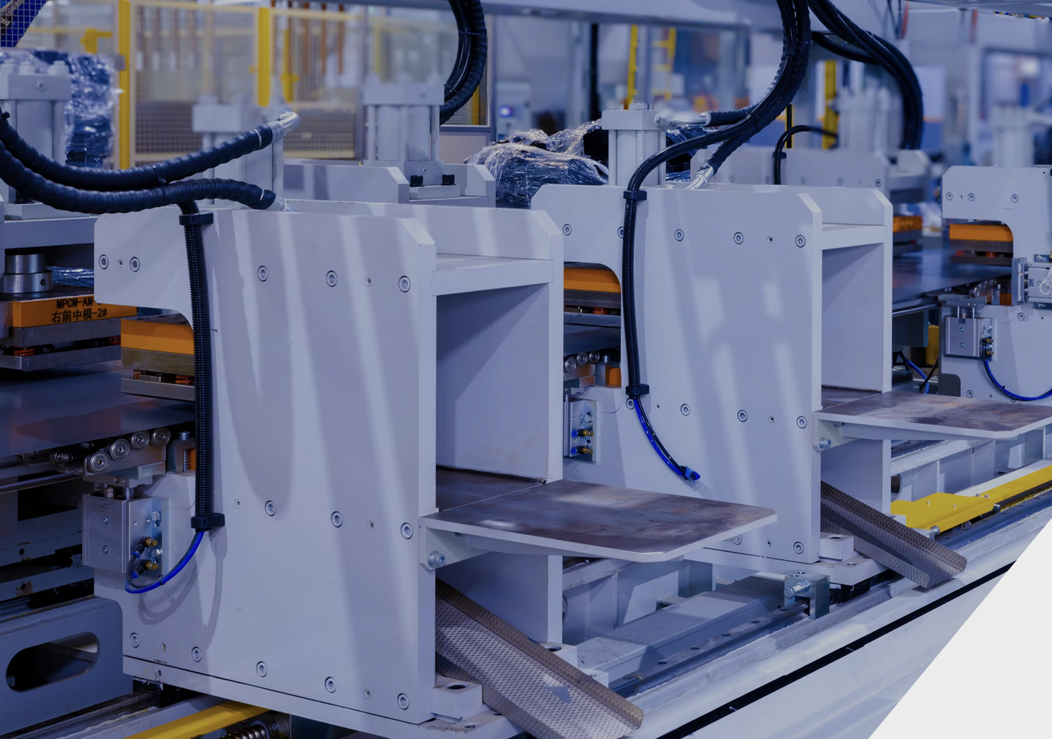 Industrial manufacturing equipment with white machinery and black cables in a factory setting.