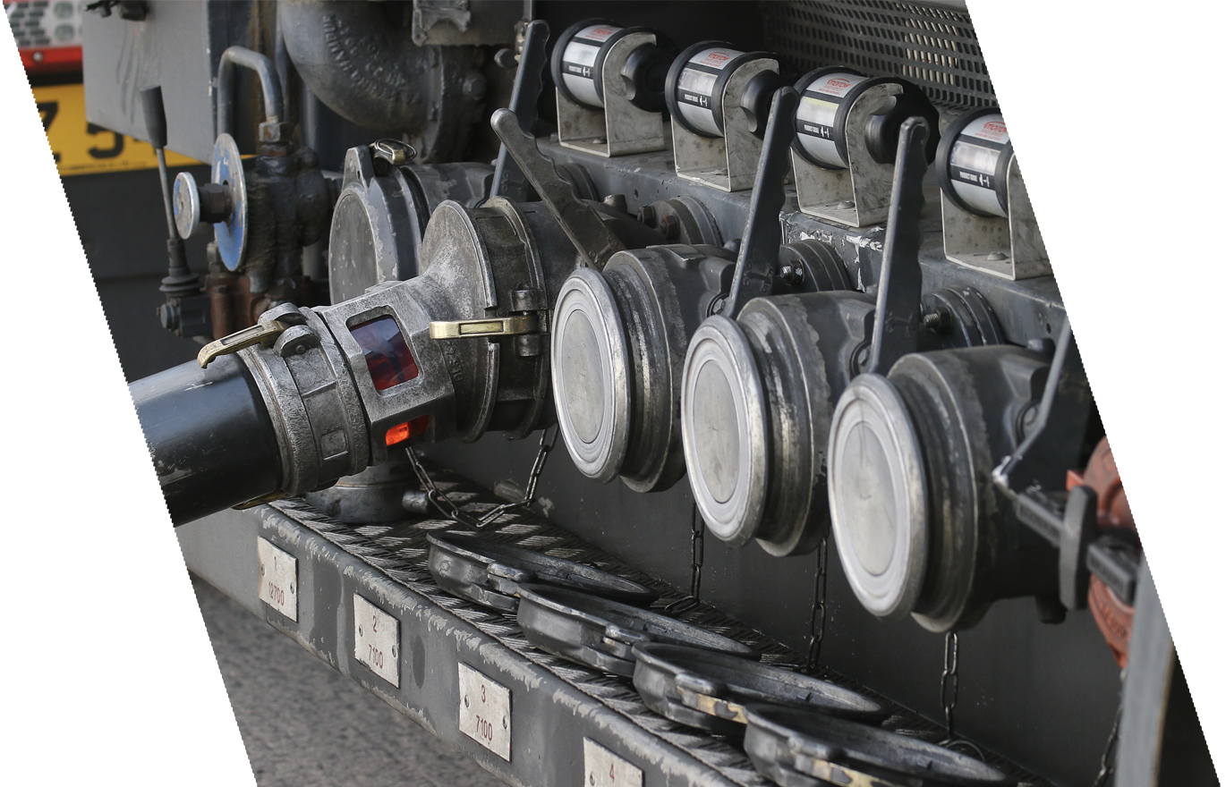 Close-up of a large industrial machine component with multiple circular metallic parts, valves, and chains, mounted on a metal platform with numbered labels.