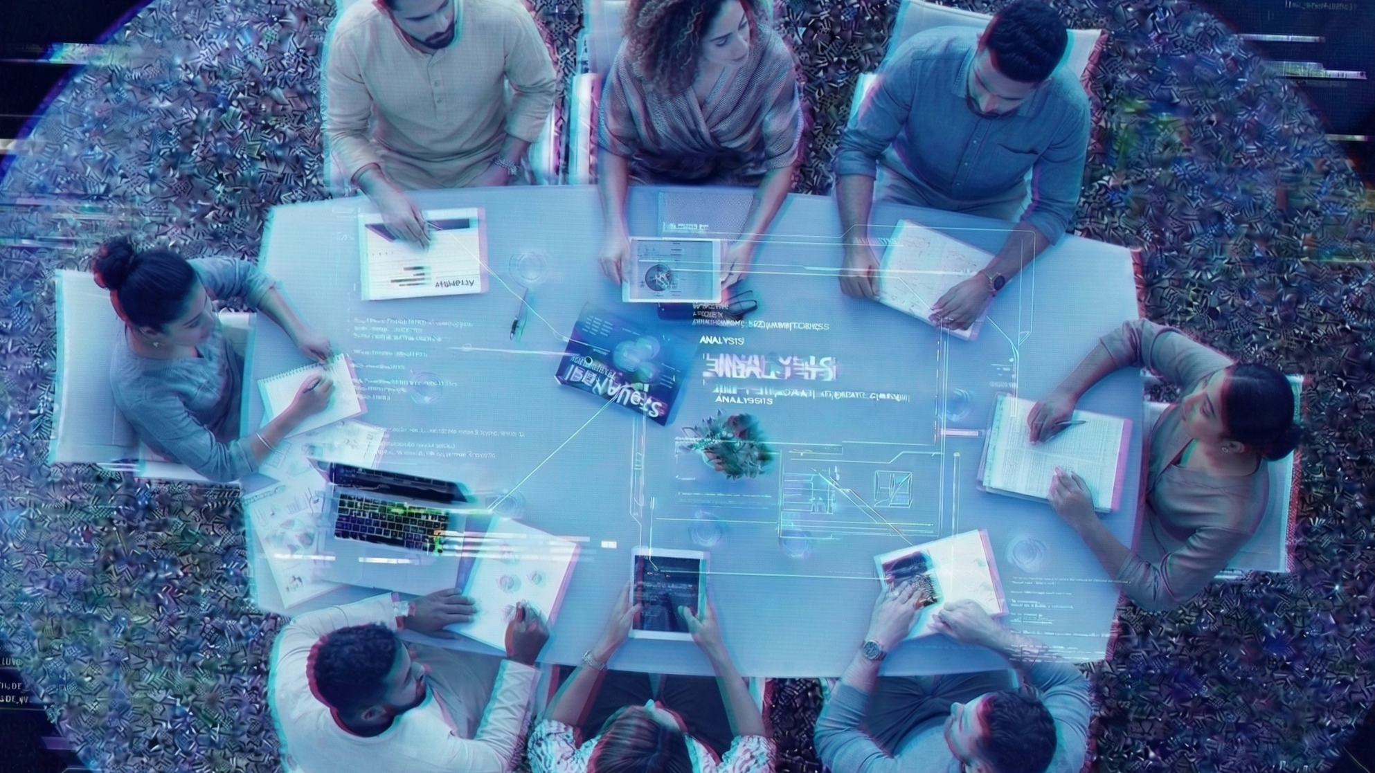 Overhead view of a diverse group of eight people gathered around a white conference table with holographic images and charts displayed on the surface, working with notebooks, tablets, and laptops in a high-tech office setting.