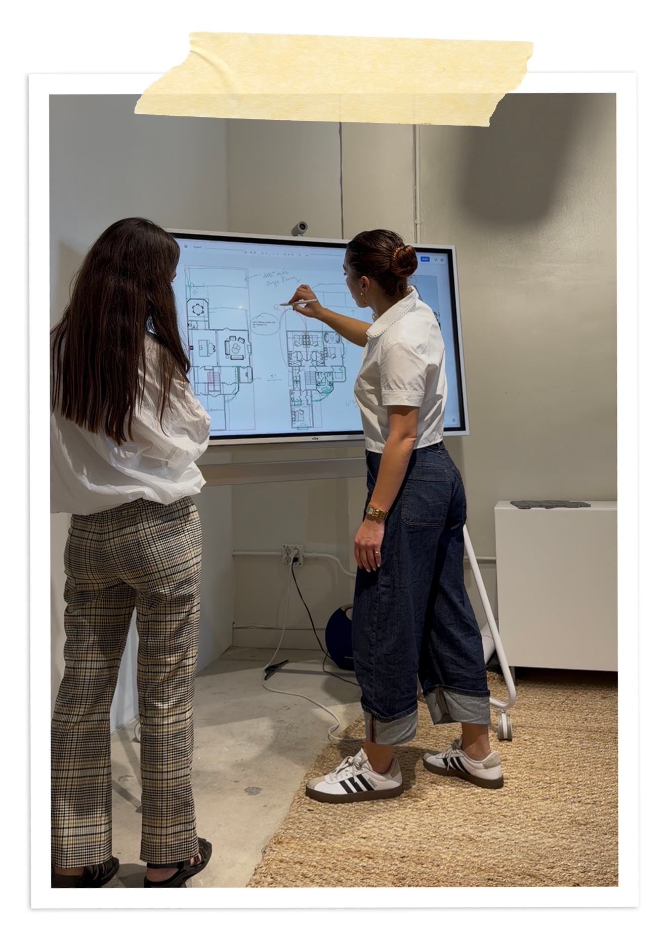 Rafi Inez sketching a floor plan on a digital whiteboard with a colleague in her studio