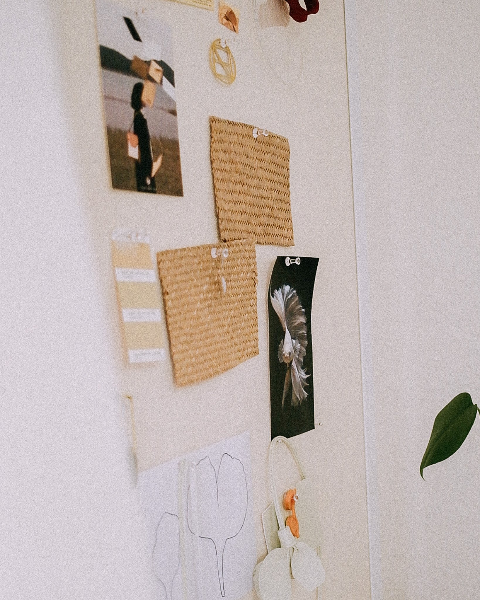 Various handmade crafts and jewelry displayed on a white wall, including woven mats, wire jewelry, photos, and decorative items.