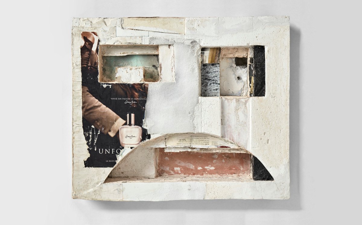 A paining made of a collage of paper scraps and pages from magazines with cut-out elemnts that makes it resembla a face with square eyes and a sad mouth.