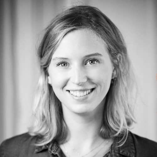 Portrait en noir et blanc d'une jeune femme souriante avec des cheveux mi-longs.