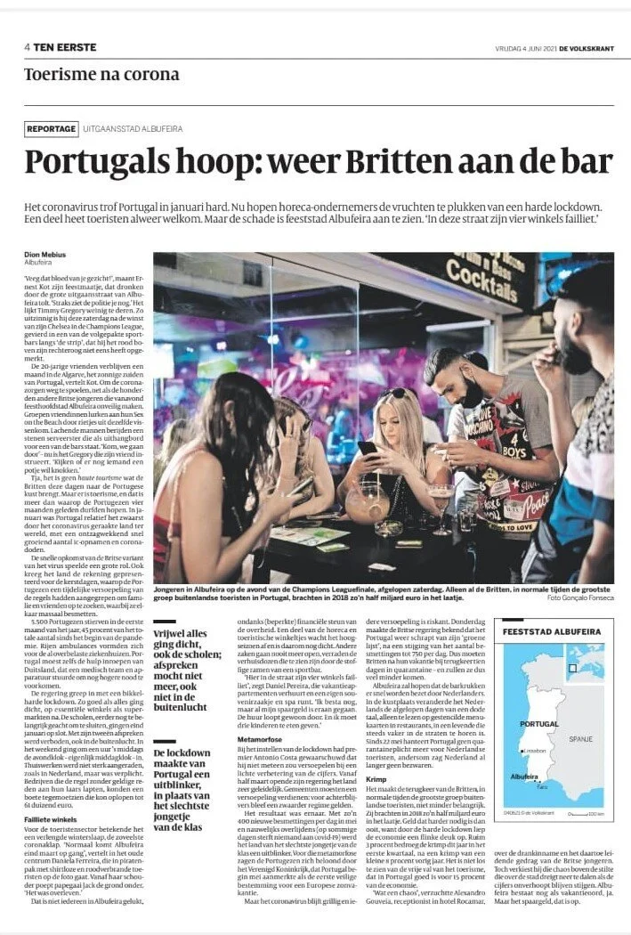 Foto de jovens em um bar ao lado de uma televisão assistindo a um jogo de futebol, com decoração colorida e ambiente animado.