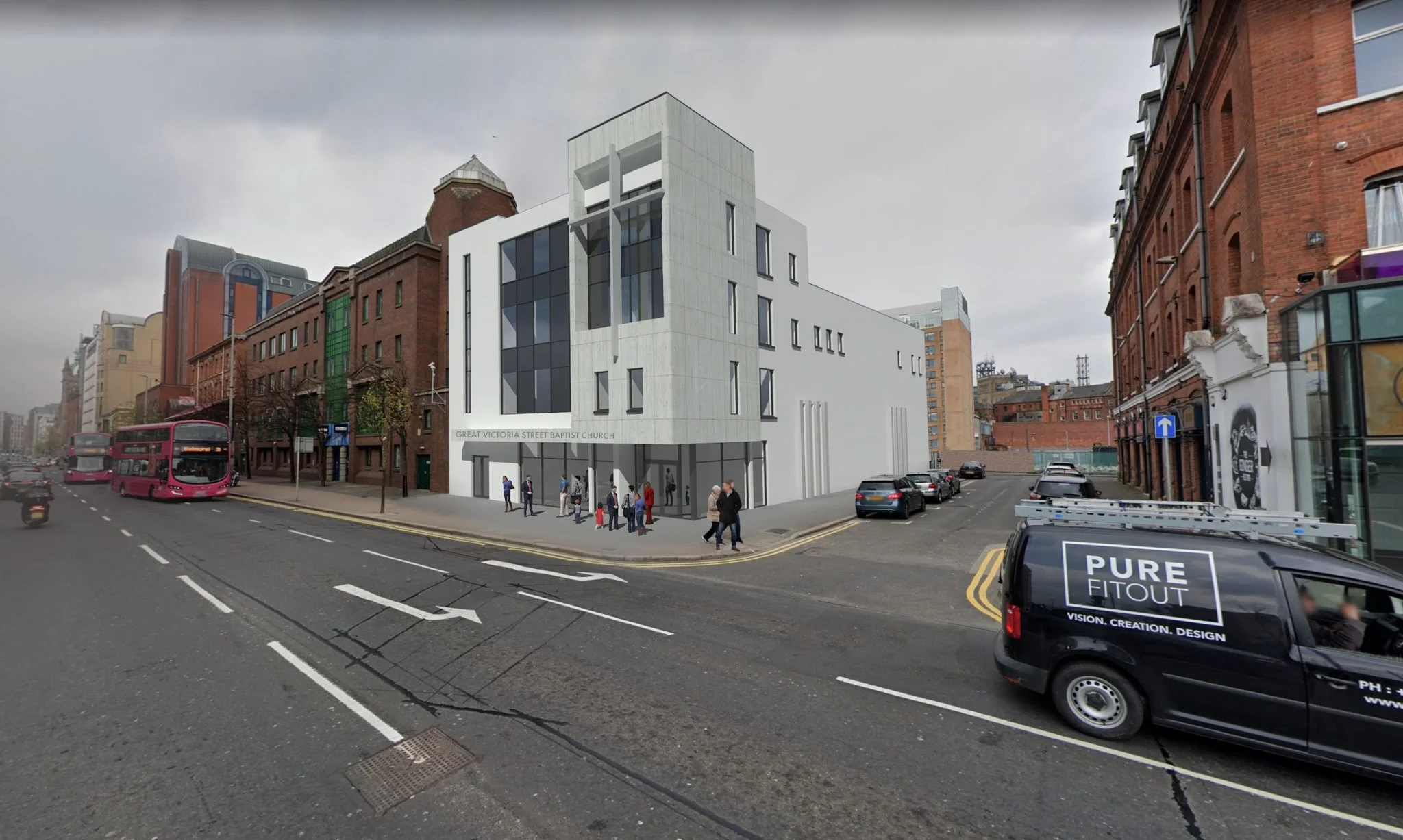 A modern white building with black windows and signs that read 'Great Victoria Street Baptist Church' on a city street corner, with people walking on the sidewalk and vehicles on the road including a pink bus and a car with advertising, under a cloudy sky.