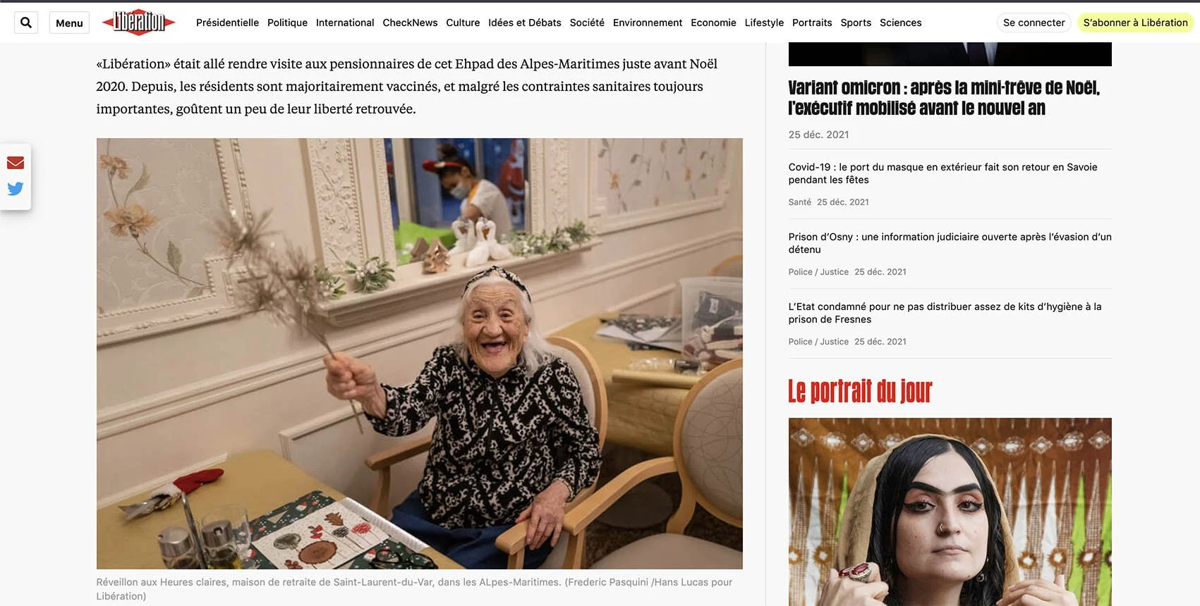 An elderly woman with white hair, smiling joyfully, holding a small branch with flowers or leaves in her right hand, sitting at a table set for dinner during Christmas, in a decorated, elegant room.