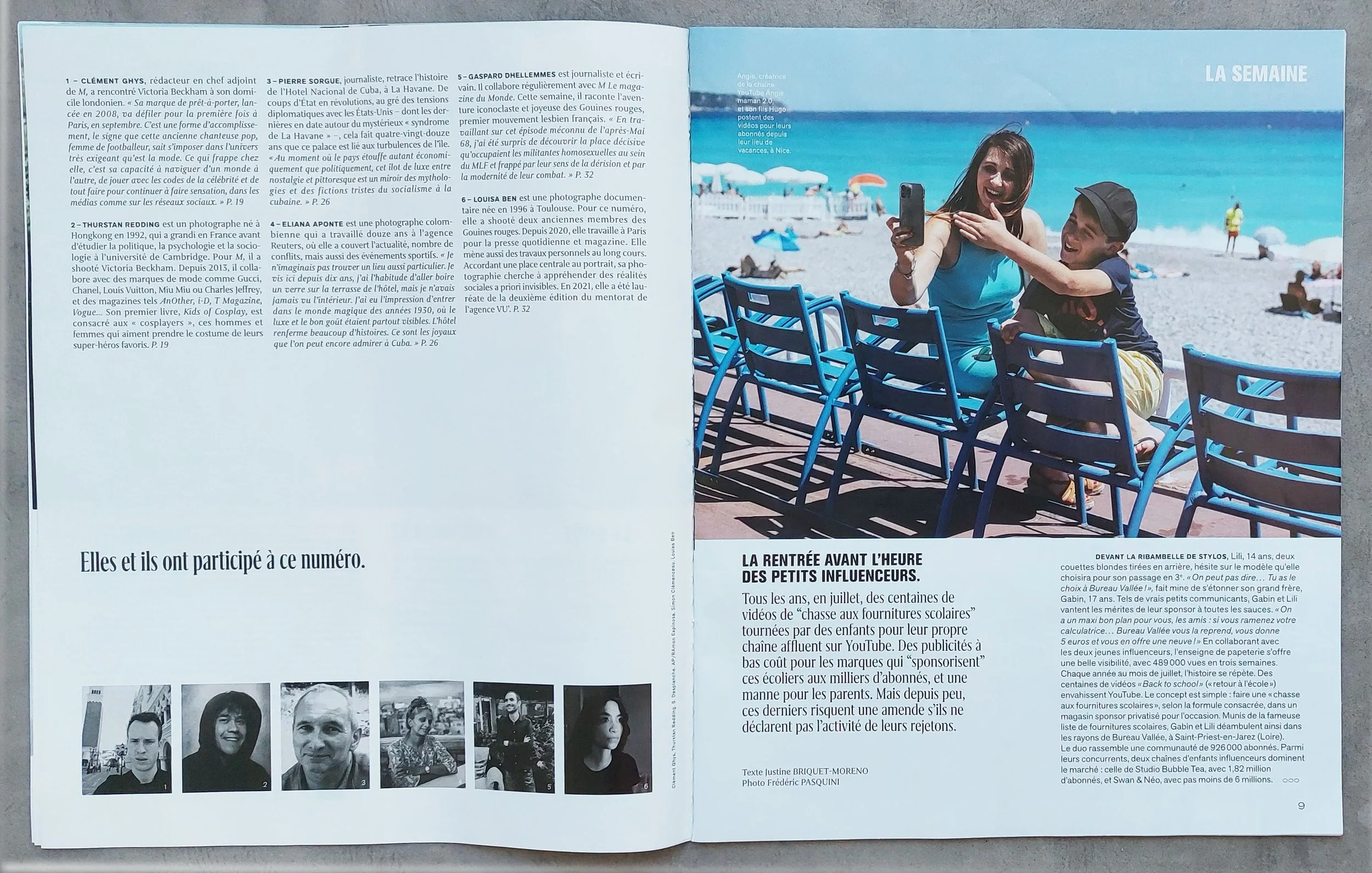 A woman and a young boy sitting at an outdoor table on a beach promenade. The woman is smiling and taking a selfie with her phone, while the boy is playfully hugging her arm. In the background, there are beach umbrellas, lounge chairs, and people on 